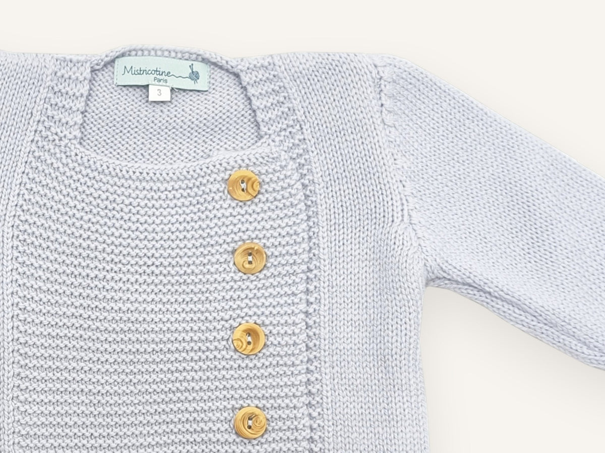 Gros plan sur l'encolure carrée et le plastron en point mousse du gilet bébé Tichat bleu ciel