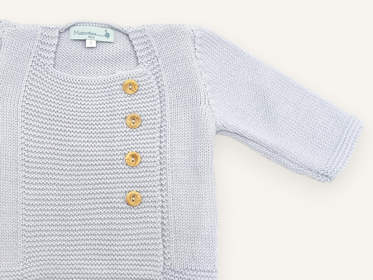 Gros plan sur l'encolure carrée et le plastron en point mousse du gilet bébé Tichat bleu ciel