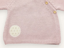 Detail of the round embroidered fabric patch and ribbed edge of the pink Didou preemie cardigan