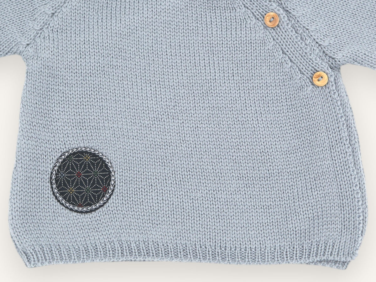 Detail of the round embroidered fabric patch and ribbed edge of the blue-grey Dadou preemie cardigan