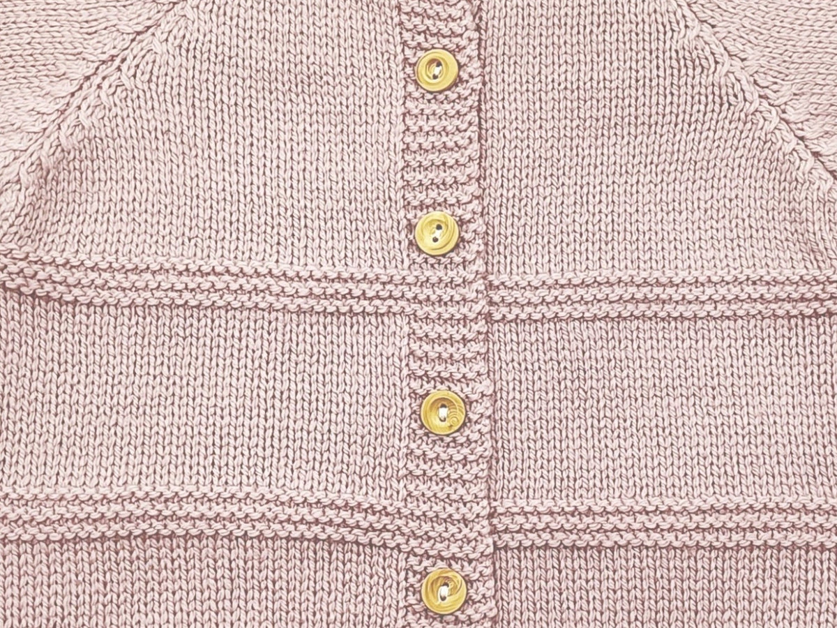 Gros plan sur le boutonnage dos, les boutons en buis et l'alternance de maille jersey et point mousse de la brassière prématuré Zazou rose
