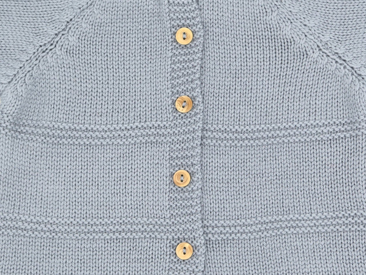 Gros plan sur le boutonnage dos, les boutons en buis et l'alternance de maille jersey et point mousse de la brassière bébé Zazou gris-bleu