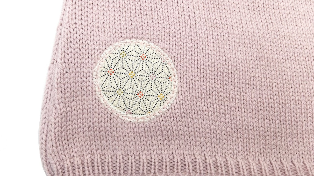 Détail d'un motif en tissu sur une brassière pour prématuré rose en laine mérinos extrafine