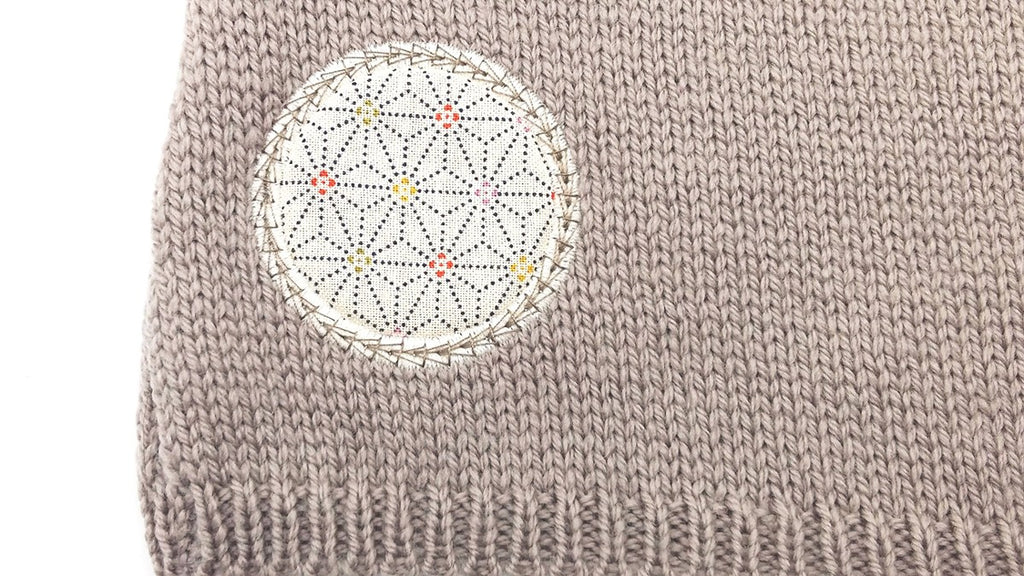 Détail d'un motif en tissu sur une brassière pour prématuré taupe en laine mérinos extrafine