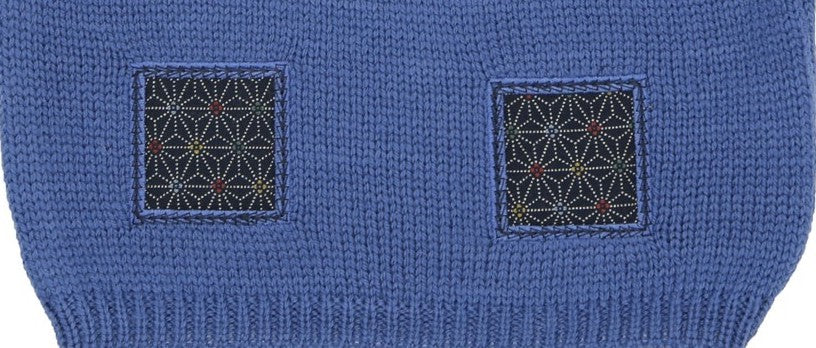 Détail des motifs en tissu sur un pull bébé en laine mérinos extrafine