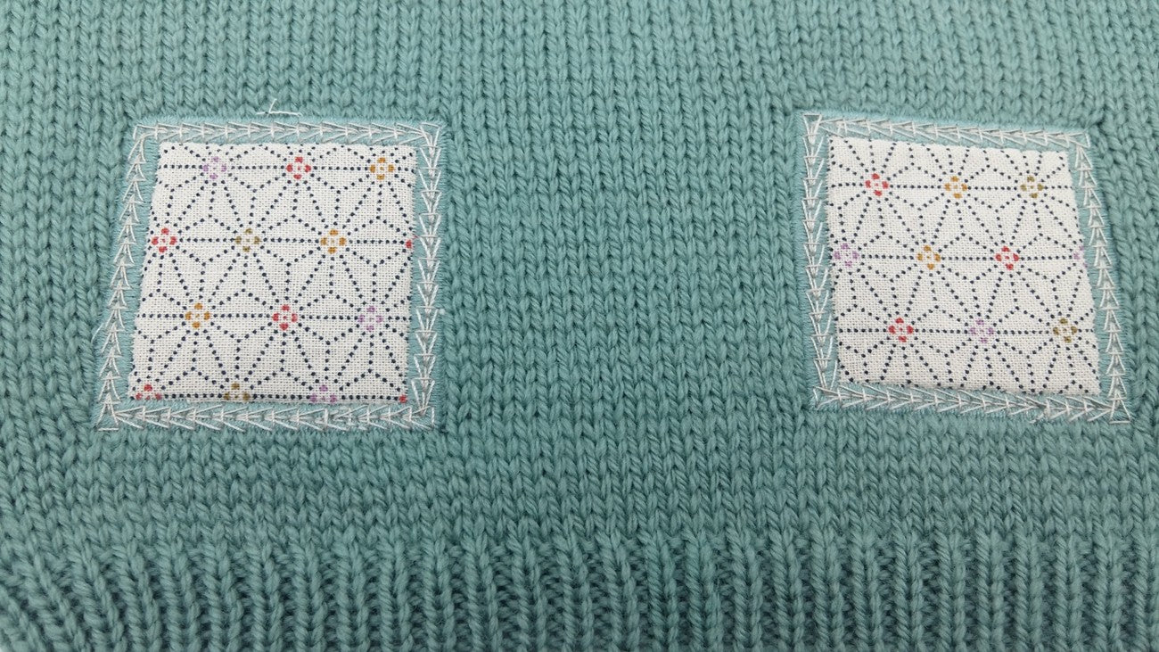 Détail des motifs en tissu sur un pull bébé en laine mérinos extrafine