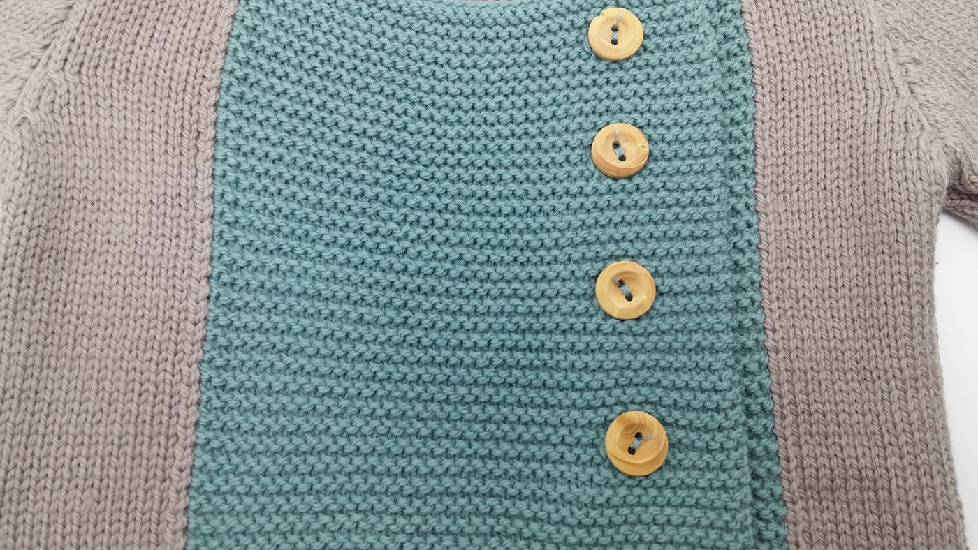 Détail du tricot d’un gilet bébé en laine mérinos extrafine