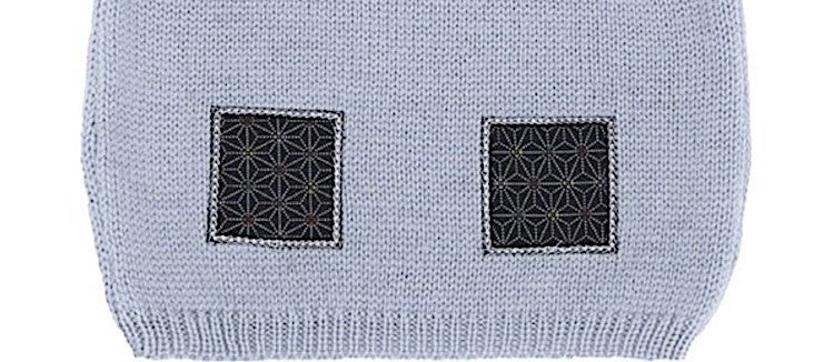 Détail des motifs en tissu sur un pull bébé en laine mérinos extrafine